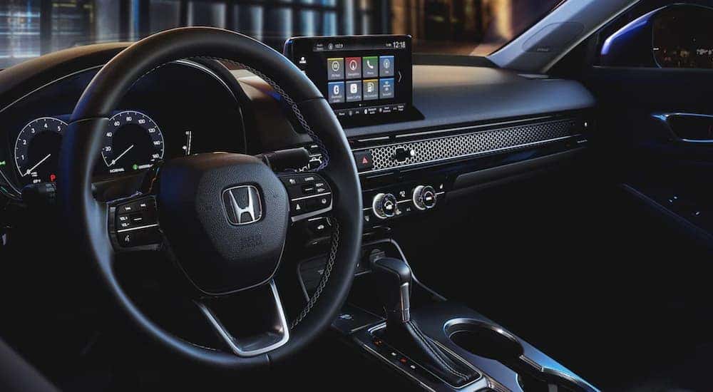 The steering wheel and infotainment screen in a black interior Honda Civic for sale.