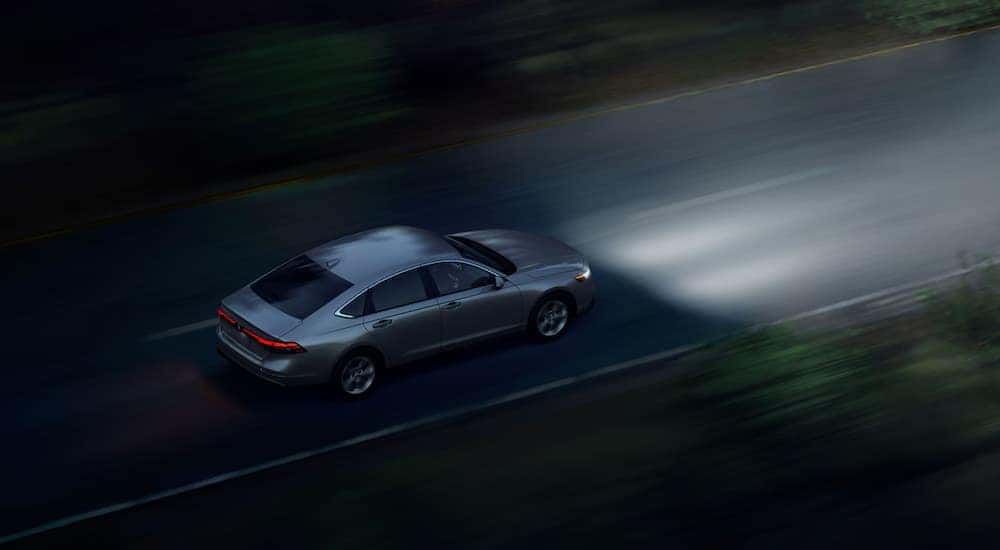 Overhead view of a 2024 Honda Accord LX driving with its headlights on at night.