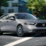 A grey 2024 Honda Accord Touring crossing through a city intersection.