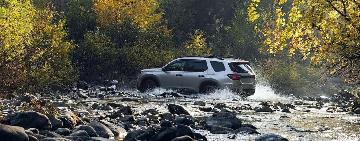 A grey 2025 Honda Pilot is shown crossing a creek.