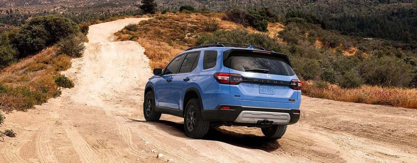 A blue 2024 Honda Pilot Trailsport is shown from the rear at an angle.