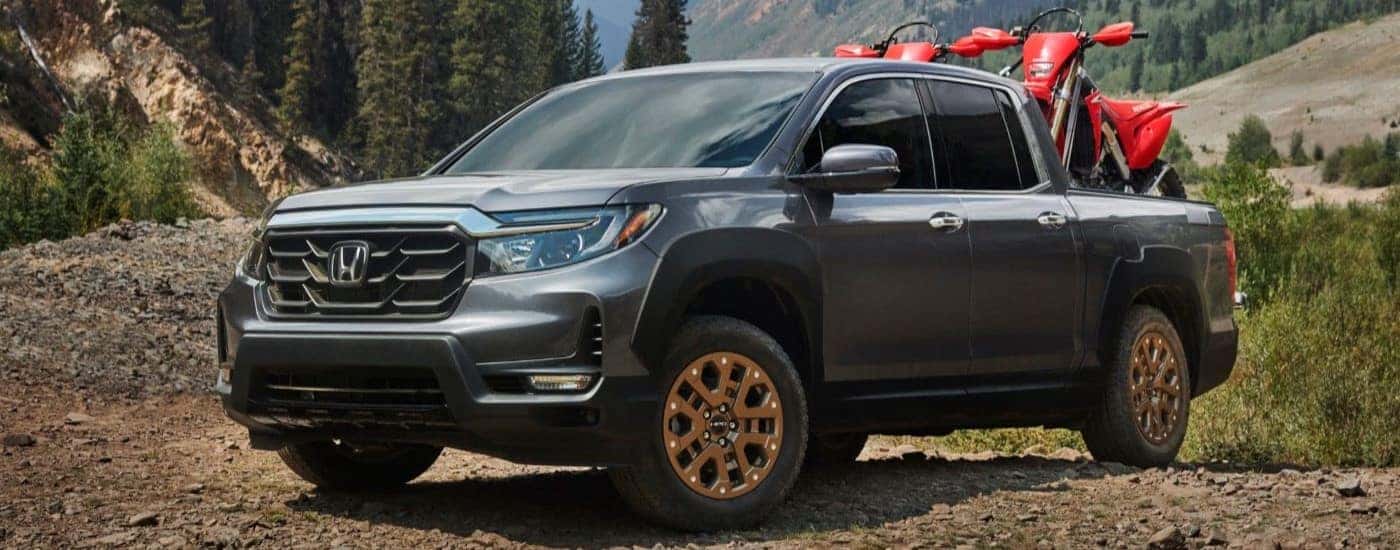 A grey 2021 Honda Ridgeline HPD parked off-road while hauling dirtbikes.