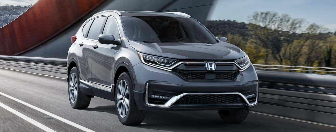 A grey 2022 Honda CR-V Hybrid driving across a bridge.