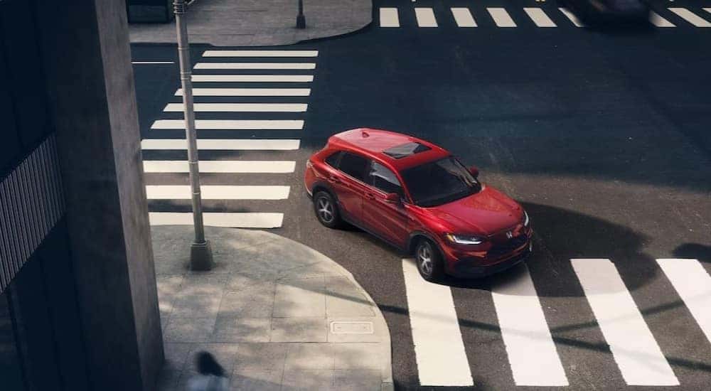 A red 2025 Honda HR-V EX-L is shown driving on a crosswalk after viewing a Honda HR-V for sale.