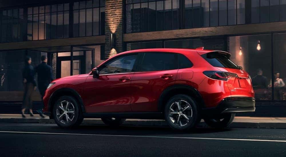 A red 2025 Honda HR-V EX-L is shown driving on a city street.