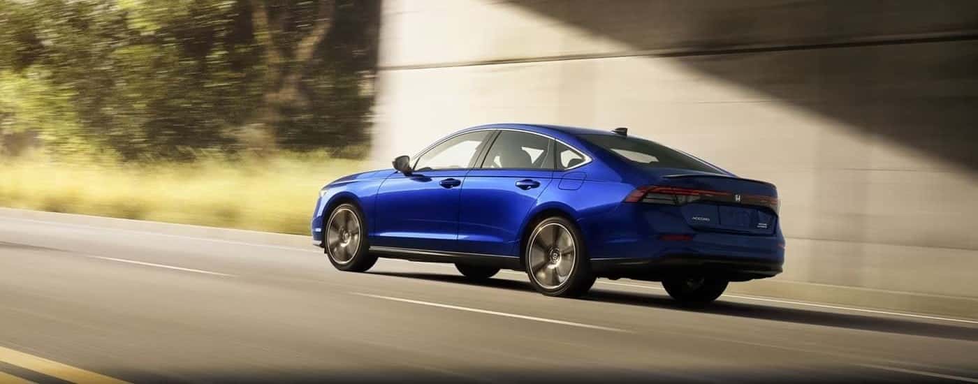 A blue 2023 Honda Accord Sports Touring is shown driving after viewing a certified pre-owned Honda.