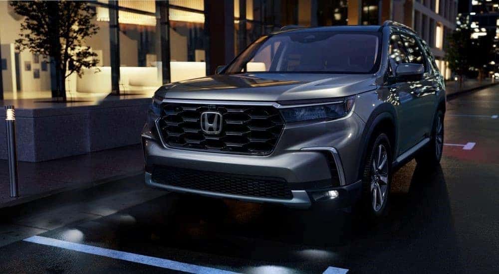 A silver 2023 Honda Pilot Elite is shown parked on a city street.
