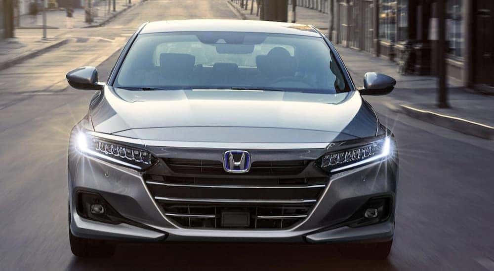 Head-on view of a silver 2022 Certified Pre-Owned Honda Accord Hybrid driving in the city.