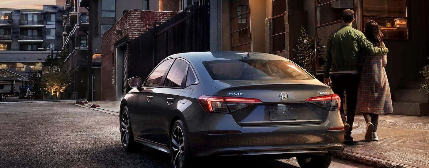 A gray 2025 Honda Civic Hybrid for sale is shown parked on a city street.