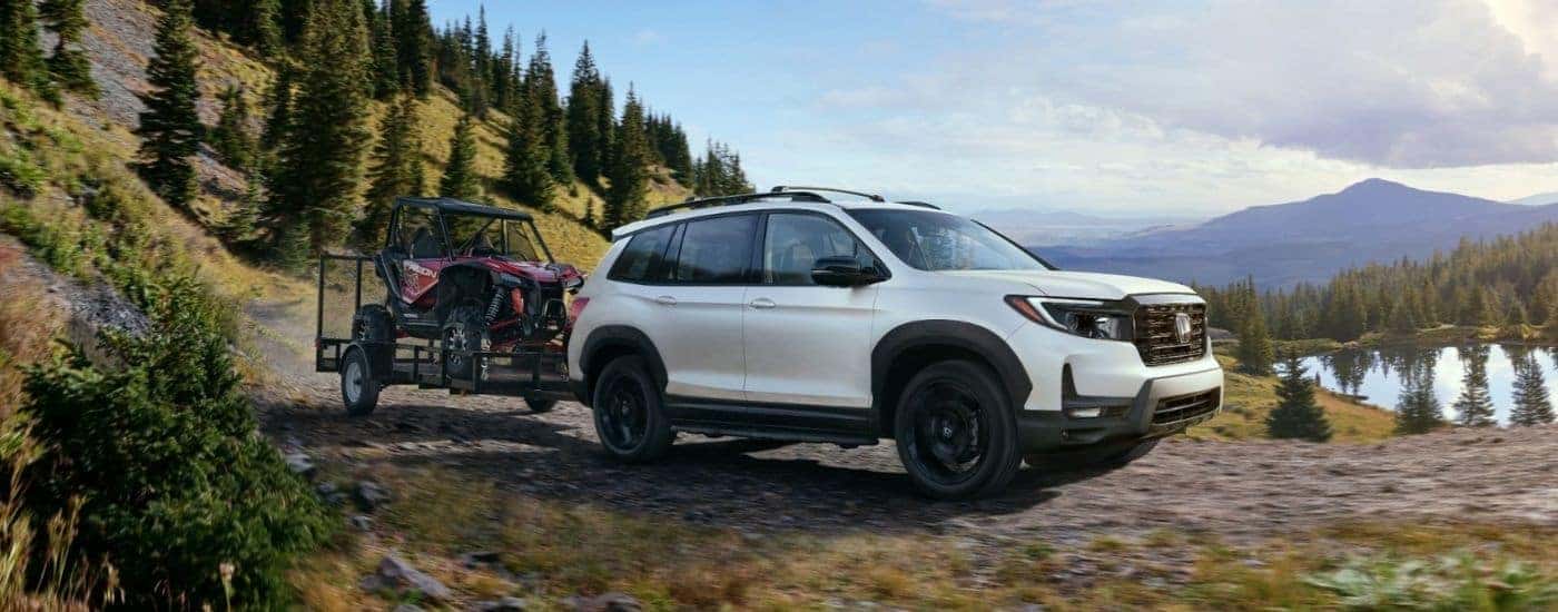 A white 2025 Honda Passport TrailSport towing ATVs.