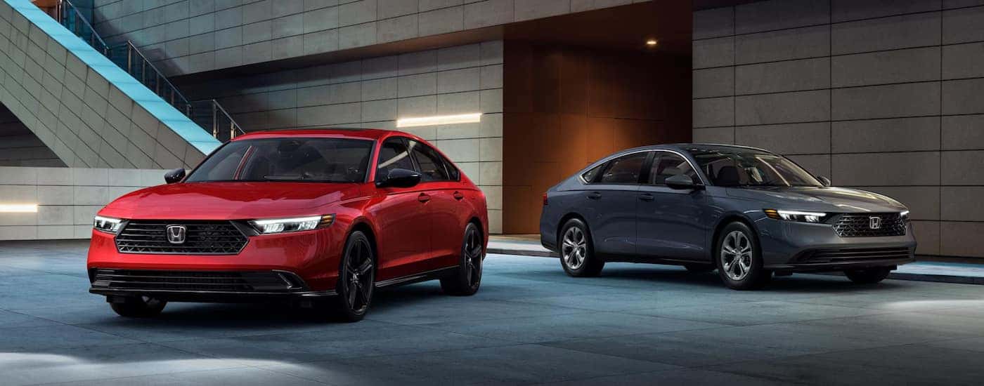A red 2024 Honda Accord Hybrid Sport-L and a grey 2024 Honda Accord LX parked outside an Oklahoma City Honda dealer.