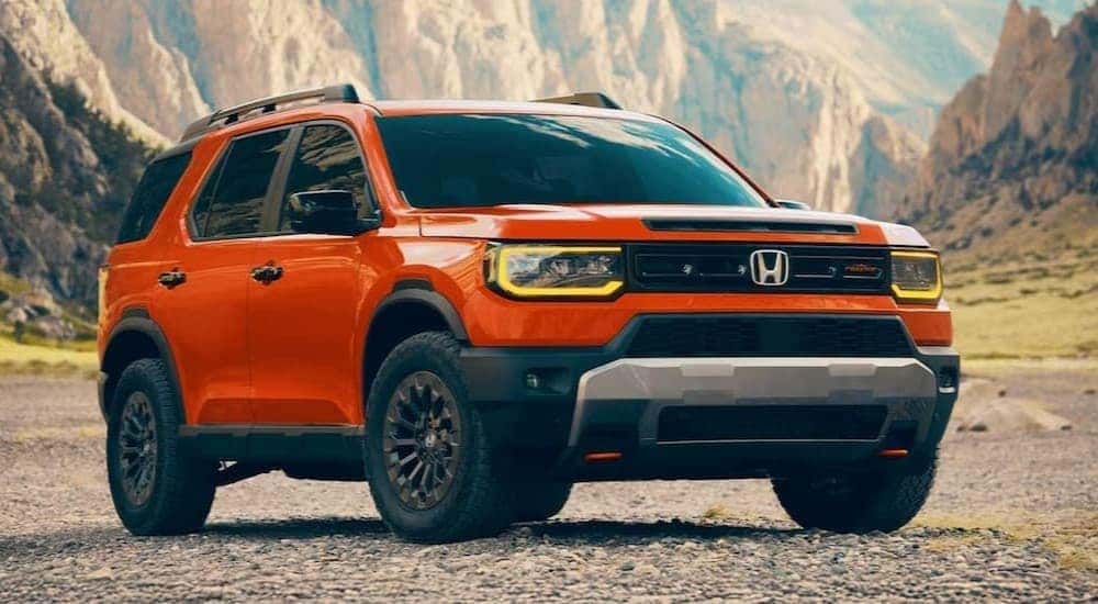 An orange 2026 Honda Passport TrailSport Elite is shown parked off-road.