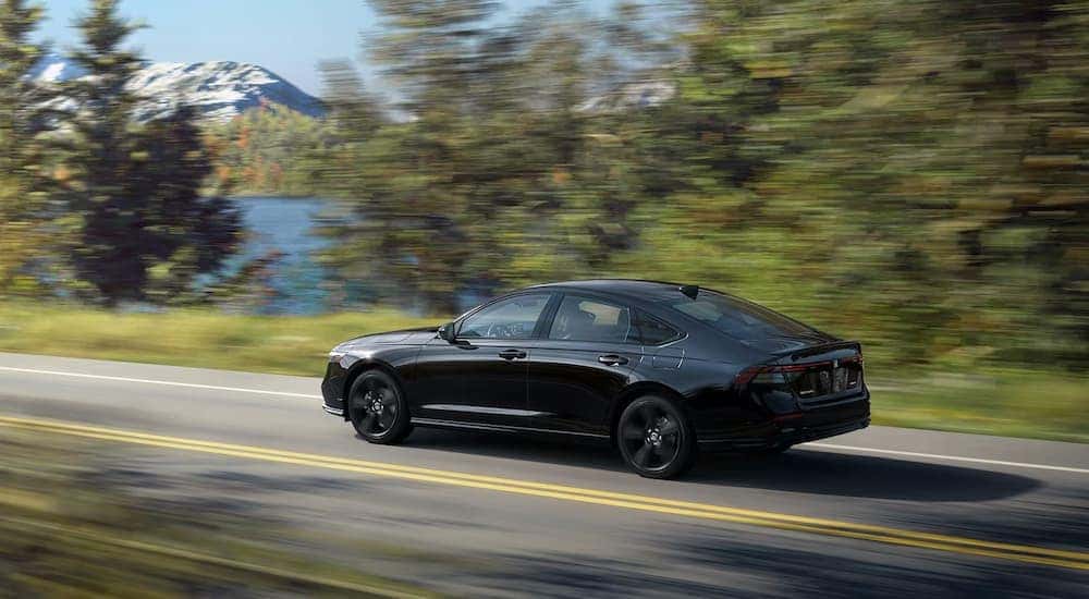 A black 2023 Honda Accord Sport is shown driving on a highway to view a used Honda Accord for sale.
