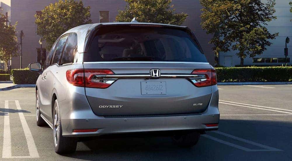 Rear view of a silver 2025 Honda Odyssey Elite parked in a parking lot.