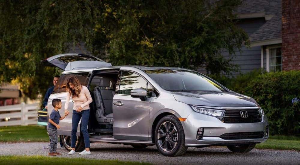A family entering a silver 2025 Honda Odyssey parked on a street.