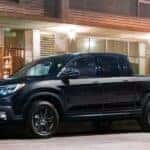A black 2020 Honda Ridgeline parked near a used car dealer.
