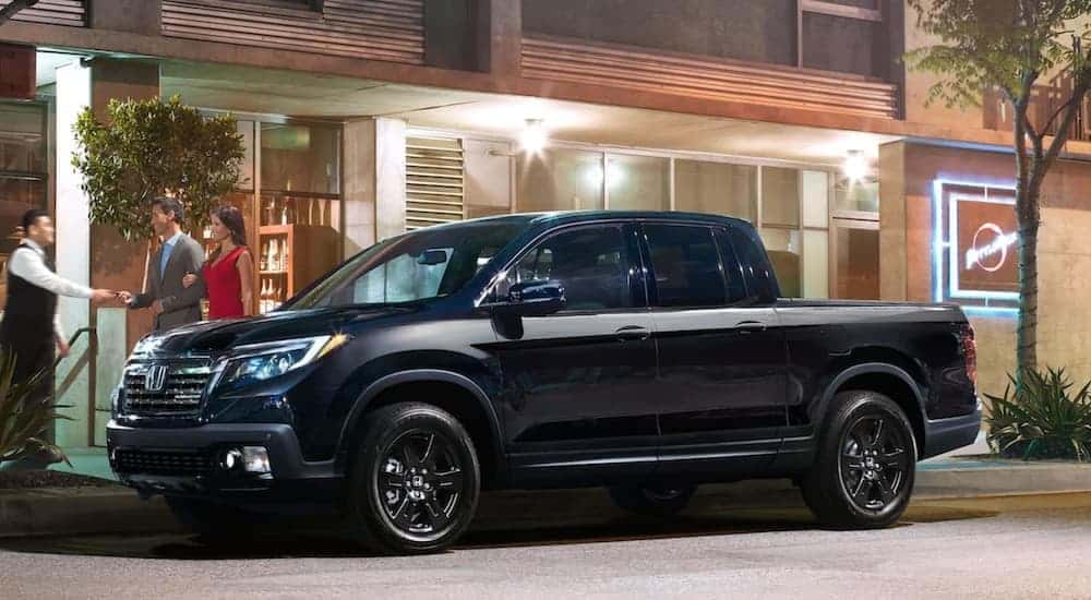 A black 2020 Honda Ridgeline parked near a used car dealer.
