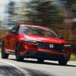 A red 2024 Honda Accord driving to a used car dealer.