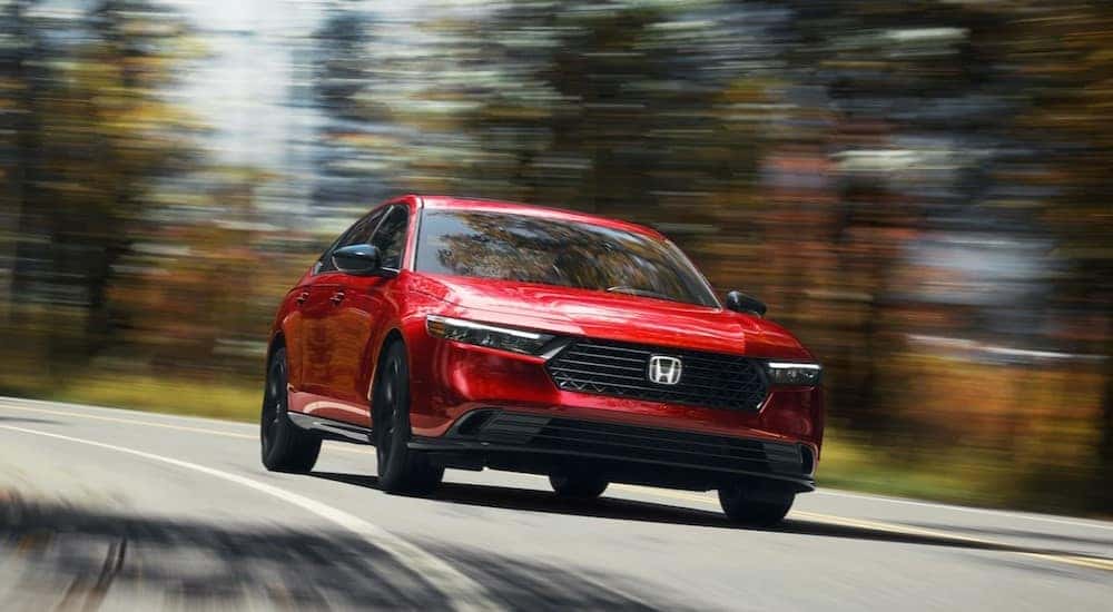 A red 2024 Honda Accord driving to a used car dealer.