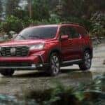 A red 2025 Honda Pilot for sale in Oklahoma City driving in the rain.