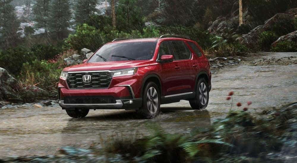 A red 2025 Honda Pilot for sale in Oklahoma City driving in the rain.
