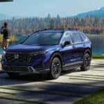 A blue 2026 Honda CR-V Sport Touring Hybrid parked near a lake.