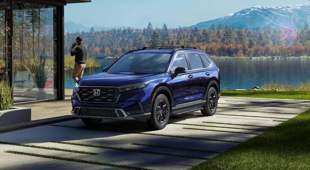 A blue 2026 Honda CR-V Sport Touring Hybrid parked near a lake.
