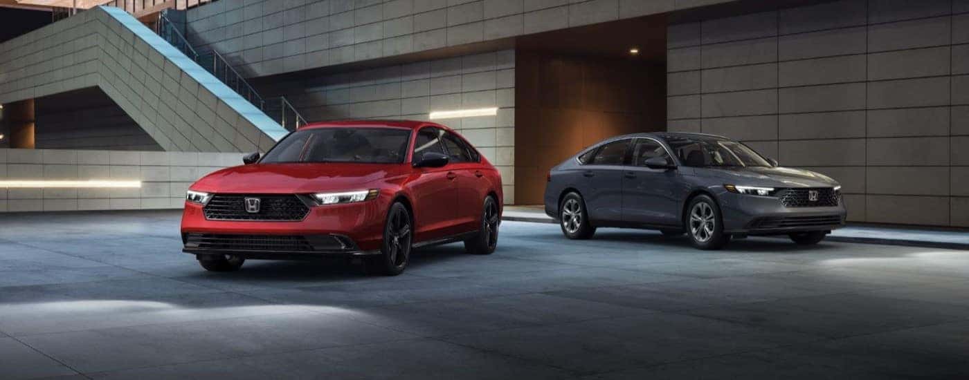 Two red and gray 2025 Honda Accord parked outside a used car dealer