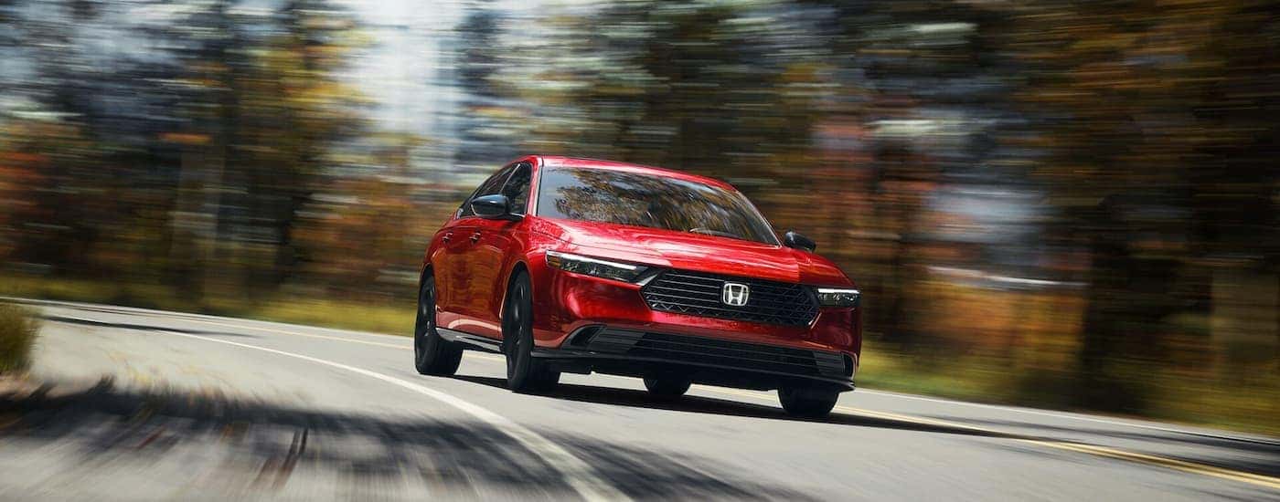 A red 2025 Honda Accord driving on a highway from a dealer near Mustang
