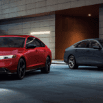 Two 2025 Honda Accord's, one red one grey, parked side by side at an angle underneath an overhand.