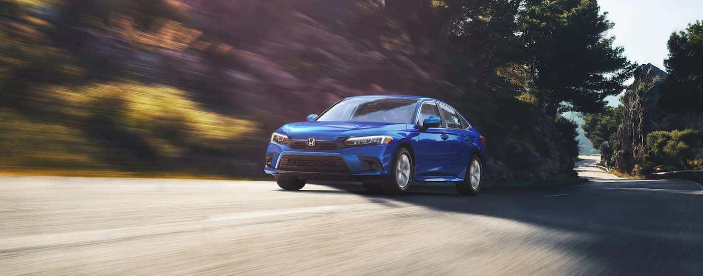 A blue 2022 Honda Civic LX driving down a road