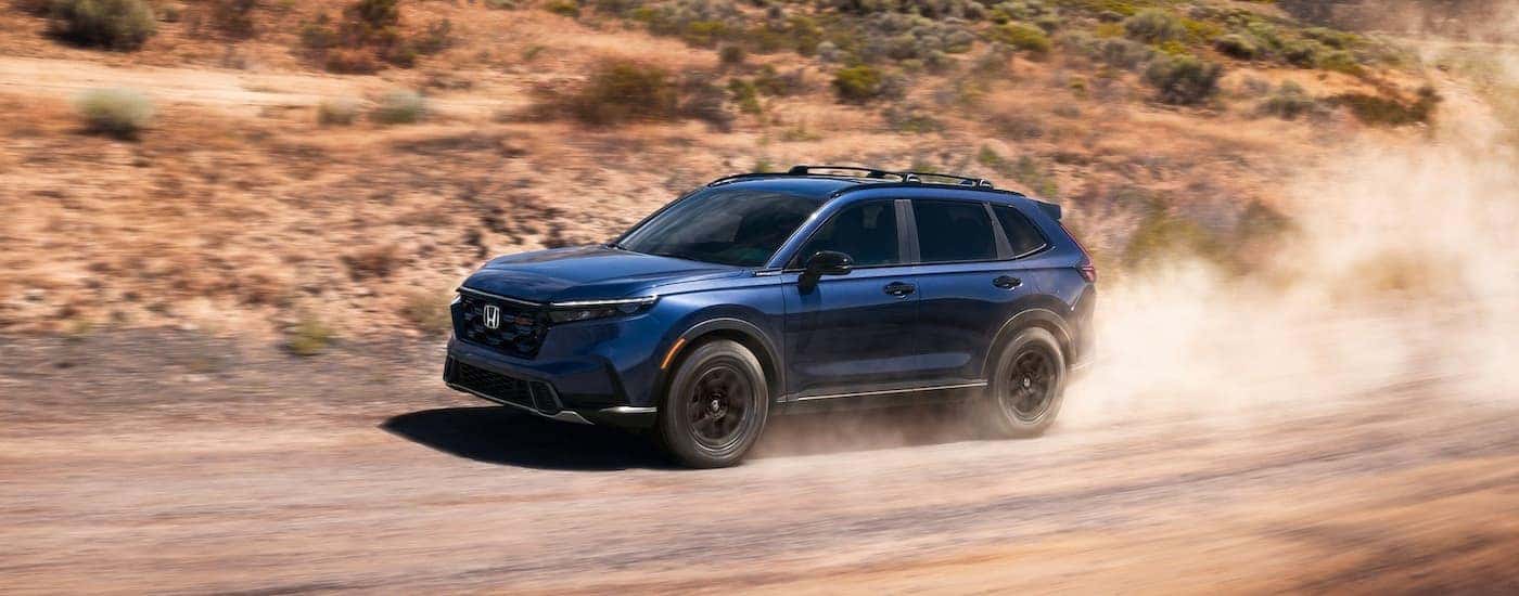 Blue 2026 Honda CR-V Hybrid driving off-road.