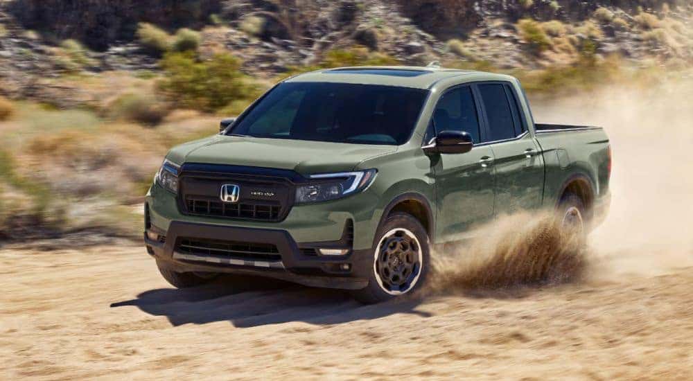 A light green 2026 Honda Ridgeline shown driving on a sandy road.