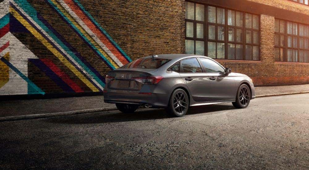 Grey 2026 Honda Civic parked next to a painted brick building.