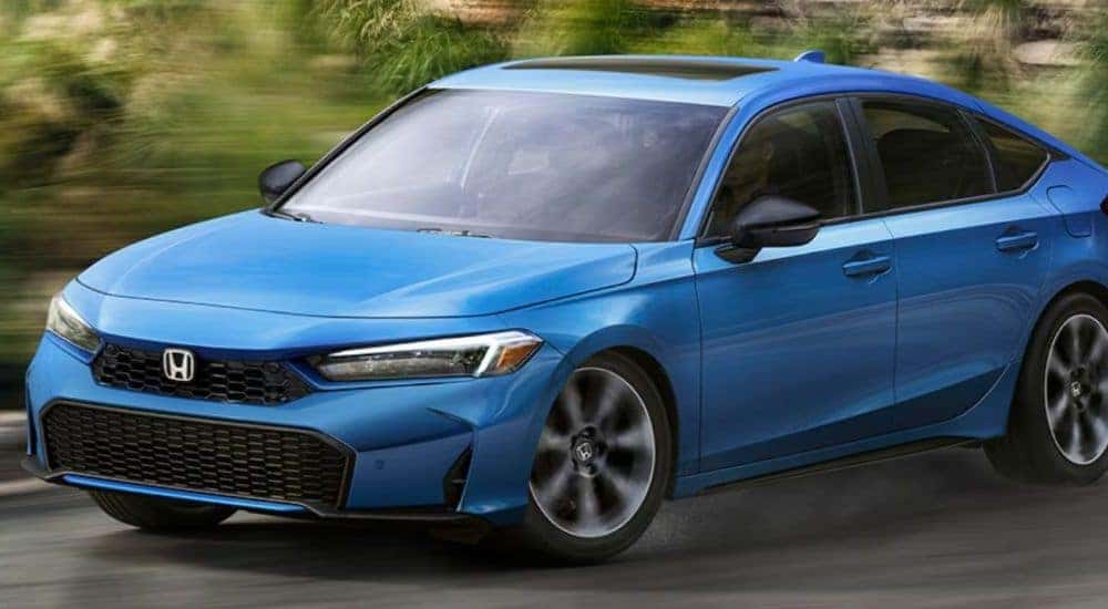 A blue 2026 Honda Civic Hatchback turning a corner on the road.