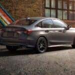 A gray 2026 Honda Civic Sport parked by a painted brick wall.