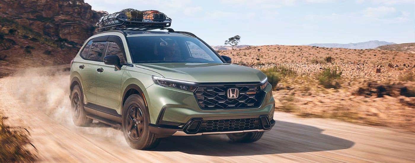 Green 2026 Honda CR-V TrailSport with camping gear on the roof driving through the desert.