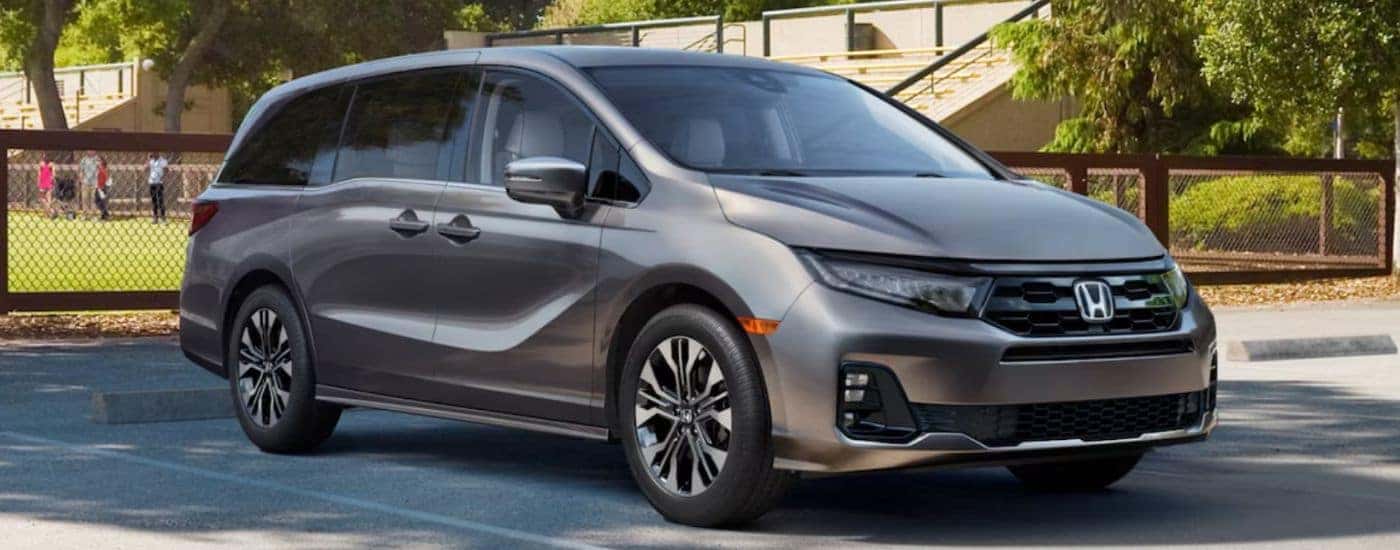 A gray 2026 Honda Odyssey Elite shown parked outside a recreational field.