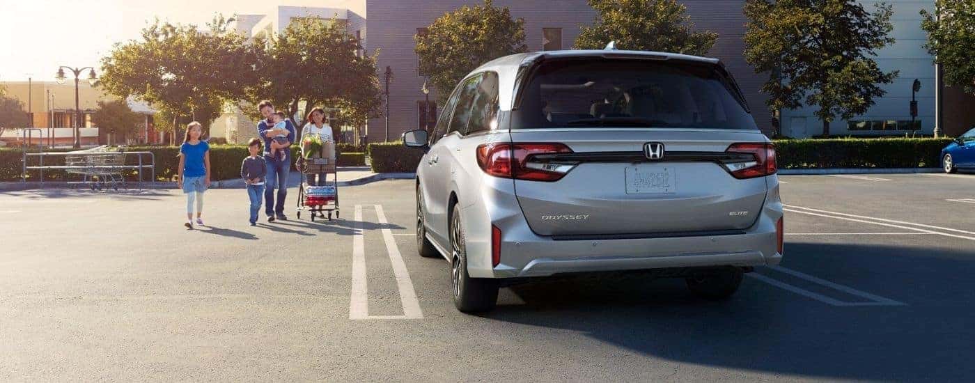 A silver 2026 Honda Odyssey Elite parked by a family with groceries..