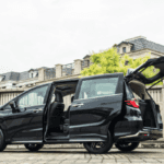 A black minivan parked outdoors with its sliding side door and rear liftgate open, showing the spacious interior.