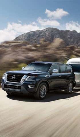 Multiple Nissan pick-up trucks are parked on a desert terrain.