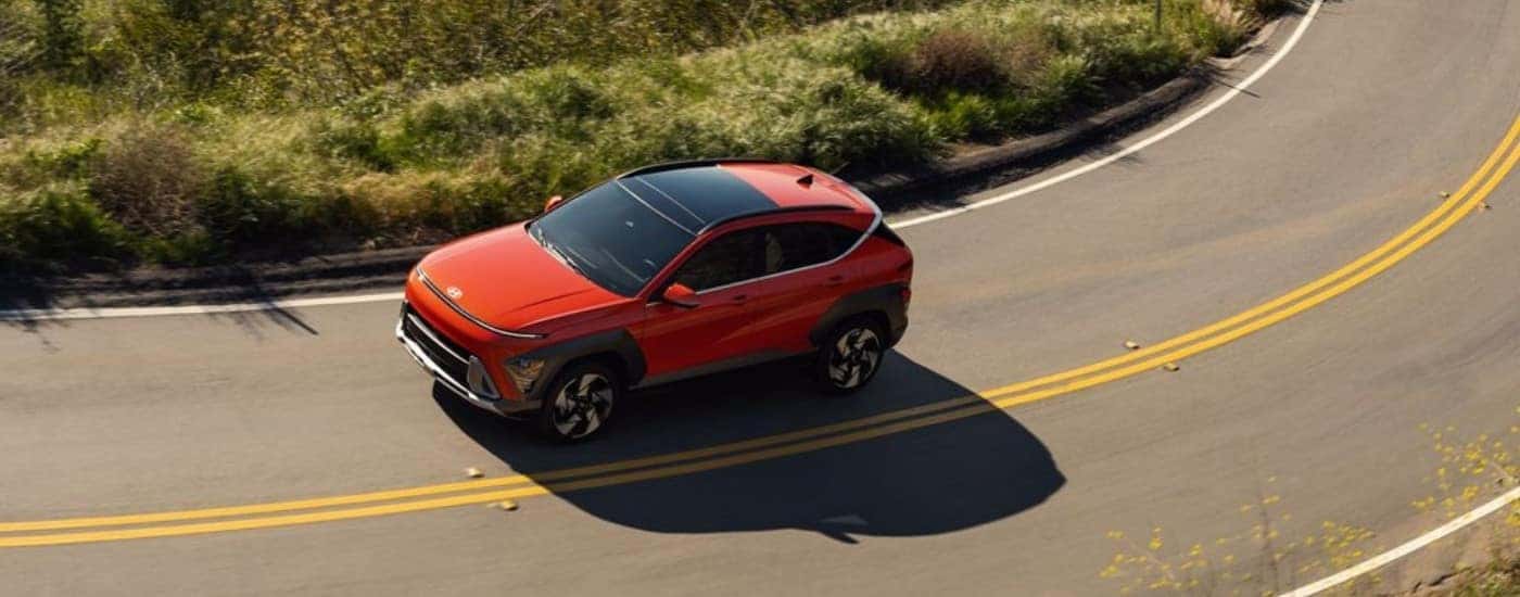 An orange 2025 Hyundai KONA for sale is shown from the side.