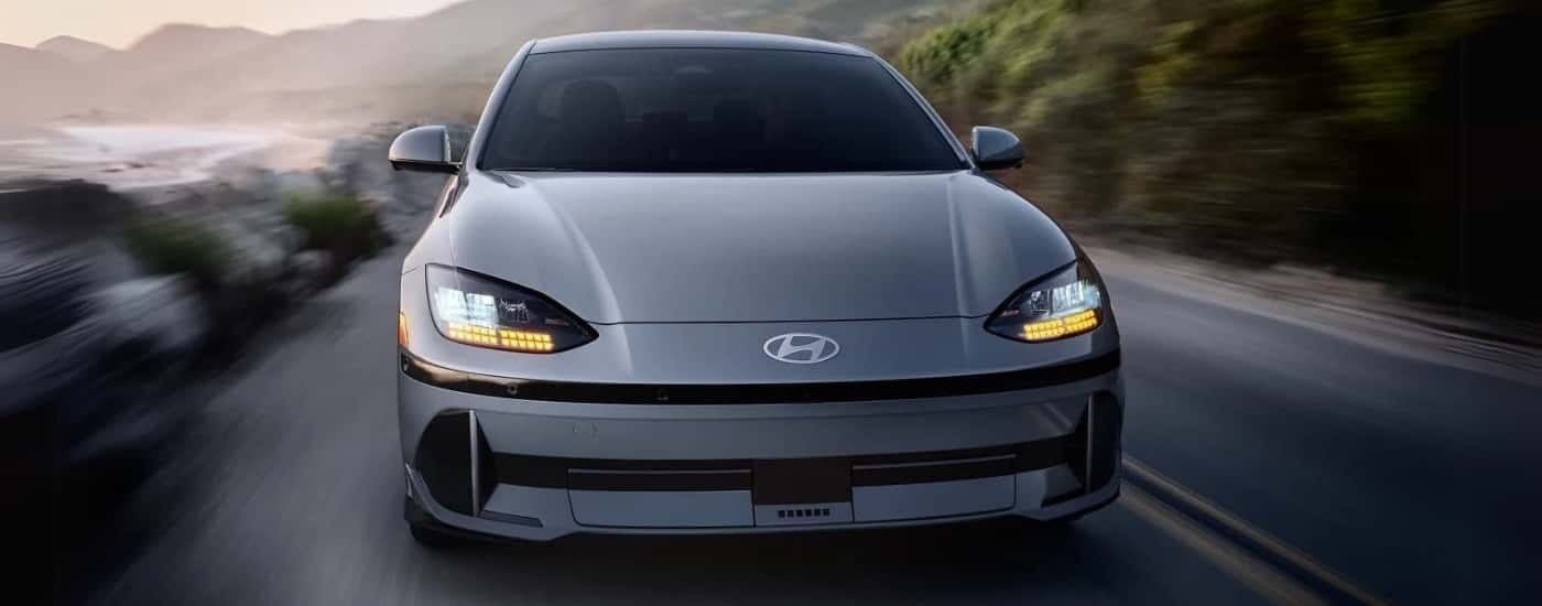 A silver 2023 Hyundai IONIQ 6 is driving past an ocean.