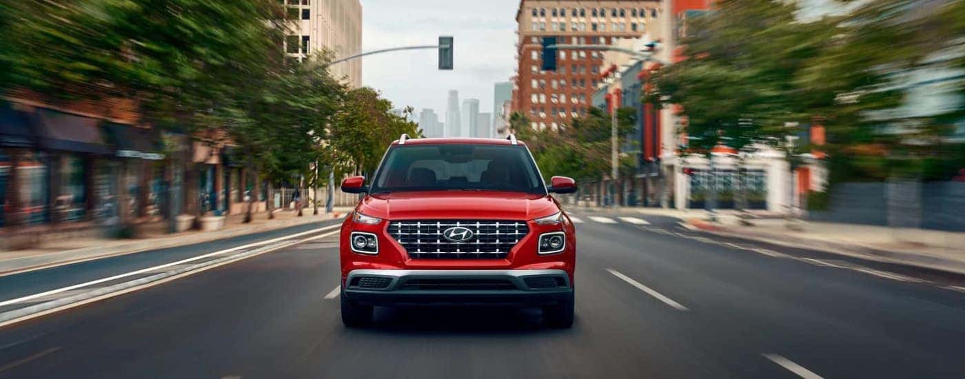 A red 2025 Hyundai Venue driving down a city street