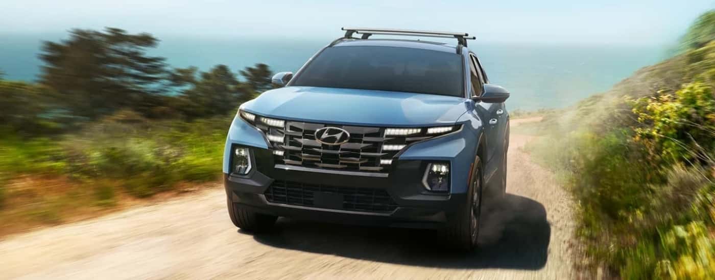 A blue 2022 Hyundai Santa Cruz is shown driving on a dusty trail.
