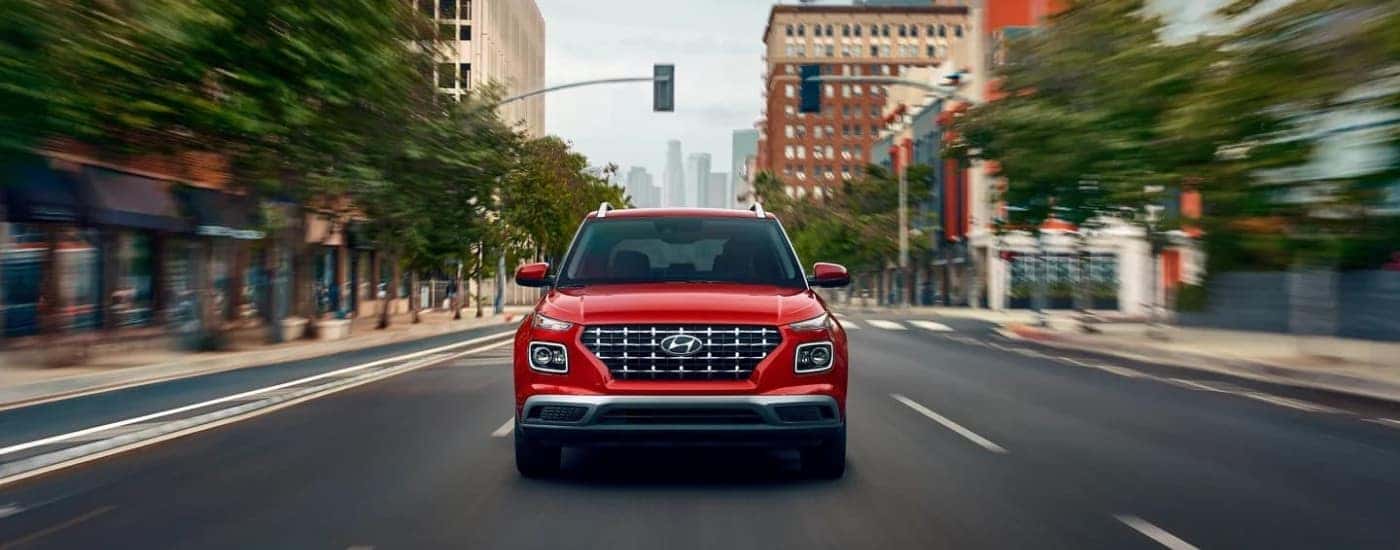 A red 2025 Hyundai Venue driving to a Hyundai dealer near you.