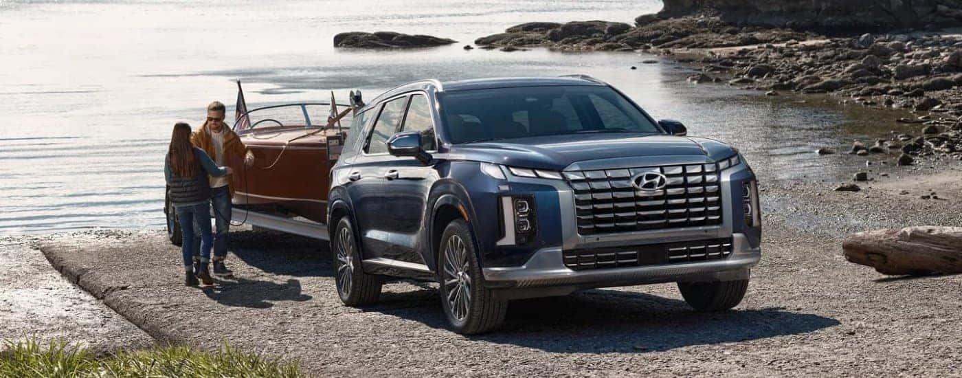 A blue 2023 Hyundai Palisade Calligraphy is towing a boat out of water.
