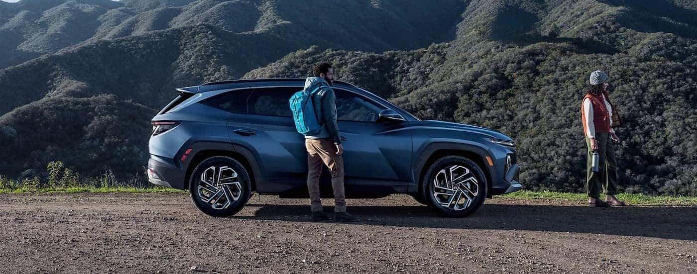 A blue 2025 Hyundai Tucson parked near two hikers.