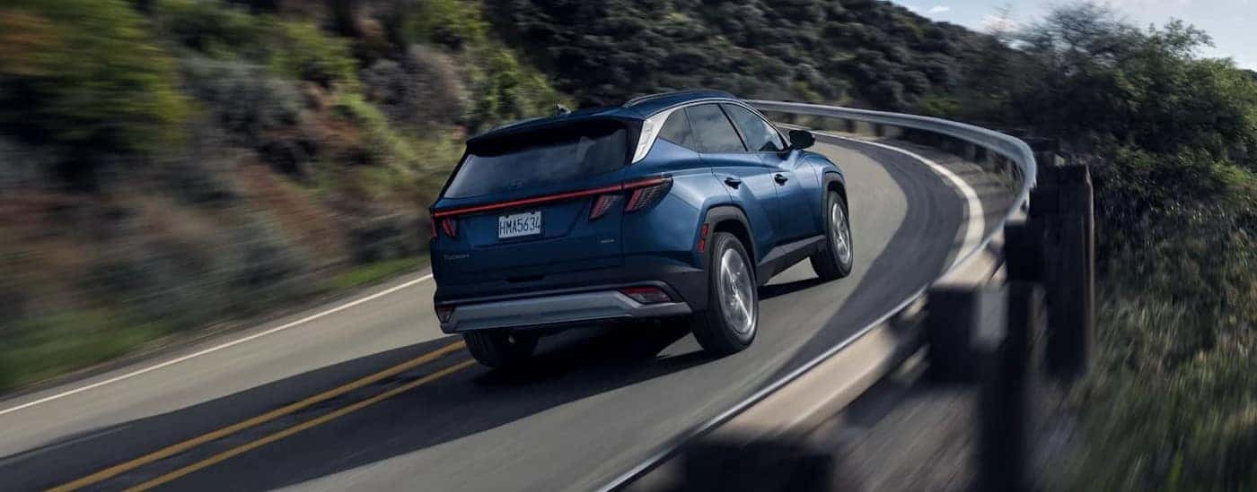A blue 2025 Hyundai Tucson driving on a highway.