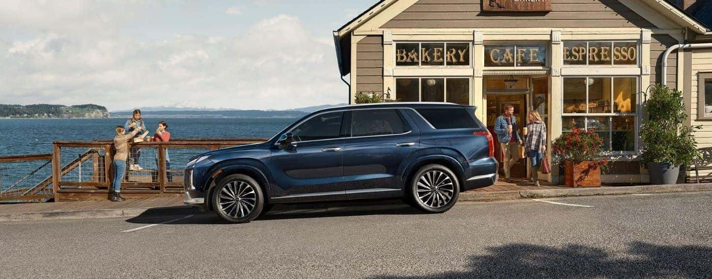 A blue 2025 Hyundai Palisade parked in front of a cafe.
